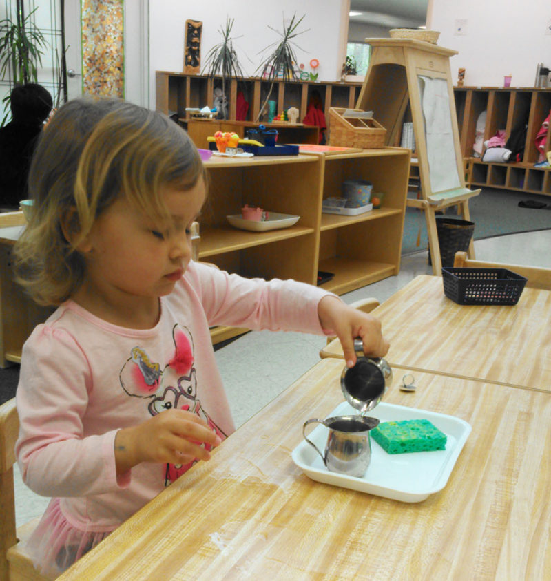 girl pouring water in Montessori class