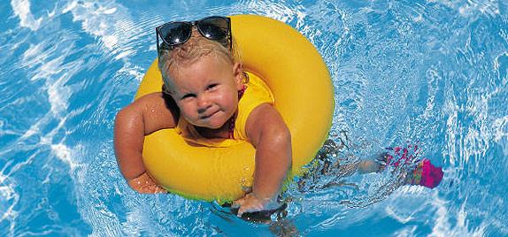 Toddler girl in rubber ring swimming