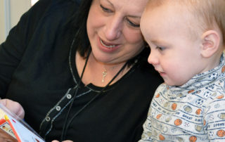 toddler enjoying a book with a teacher