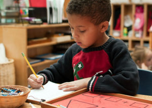 boy writing young diversity boy sitting at desk writing holly springs school