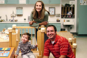 mom dad child kid toddler on play equipment inside classroom at school