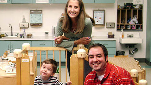 mom dad child kid toddler on play equipment inside classroom at school