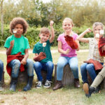 Children sitting on a log camping trip