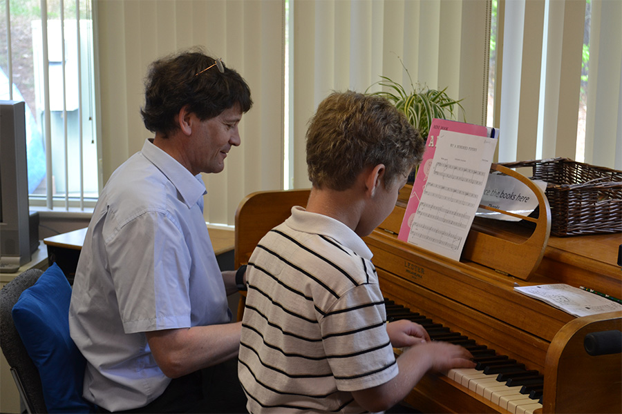 piano instructor teaching boy