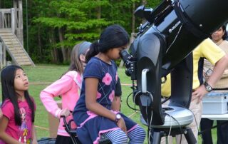 girls looking into large telescope