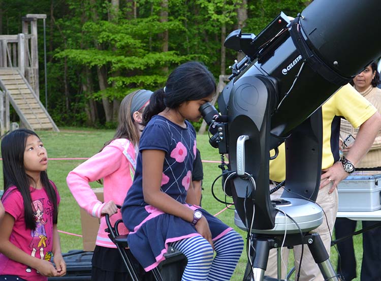 girls looking into large telescope