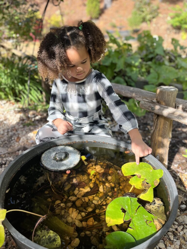 girl playing with water and plants outdoors Girl playing with water outdoors