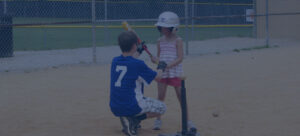 student helping young girl with baseball