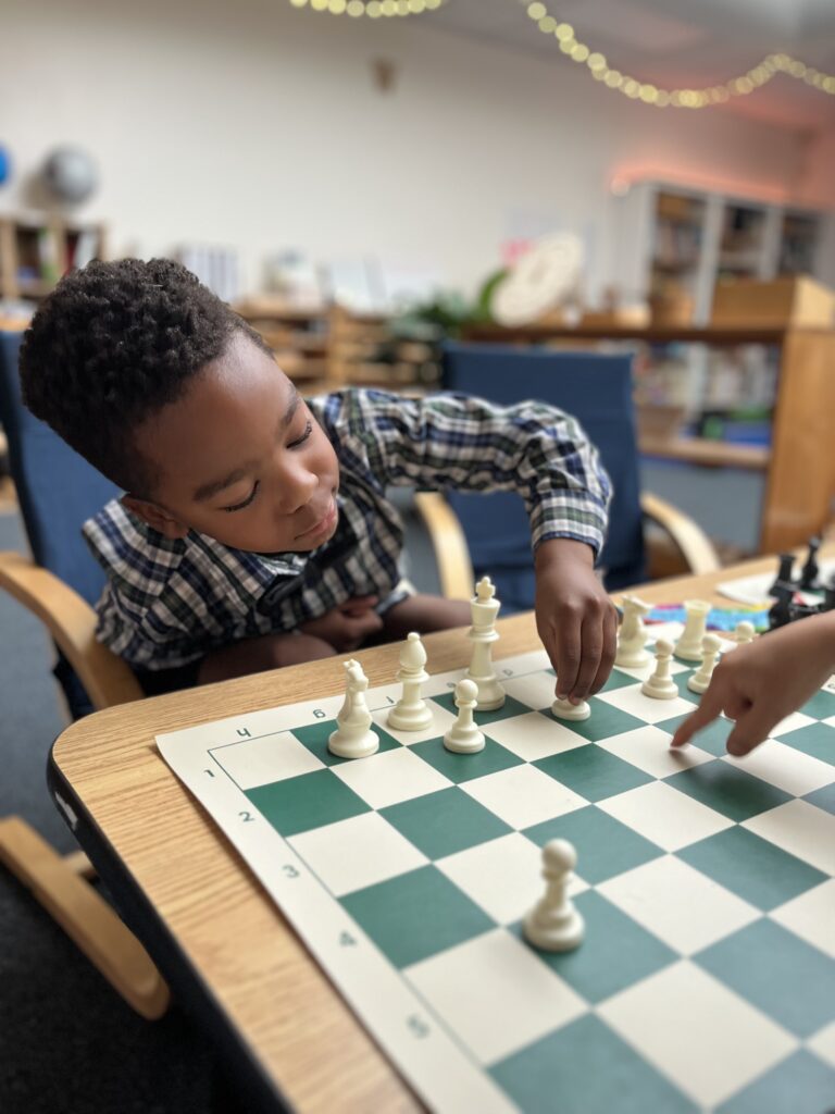 African American boy making a chess move in chess club at The New School Montessori Center