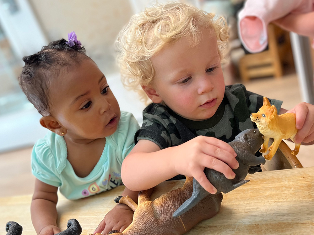 two toddlers playing with toy animals