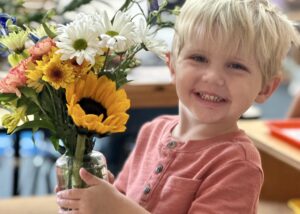 boy holding flowers in a classroom