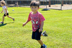 boy running in a field and smiling into camera