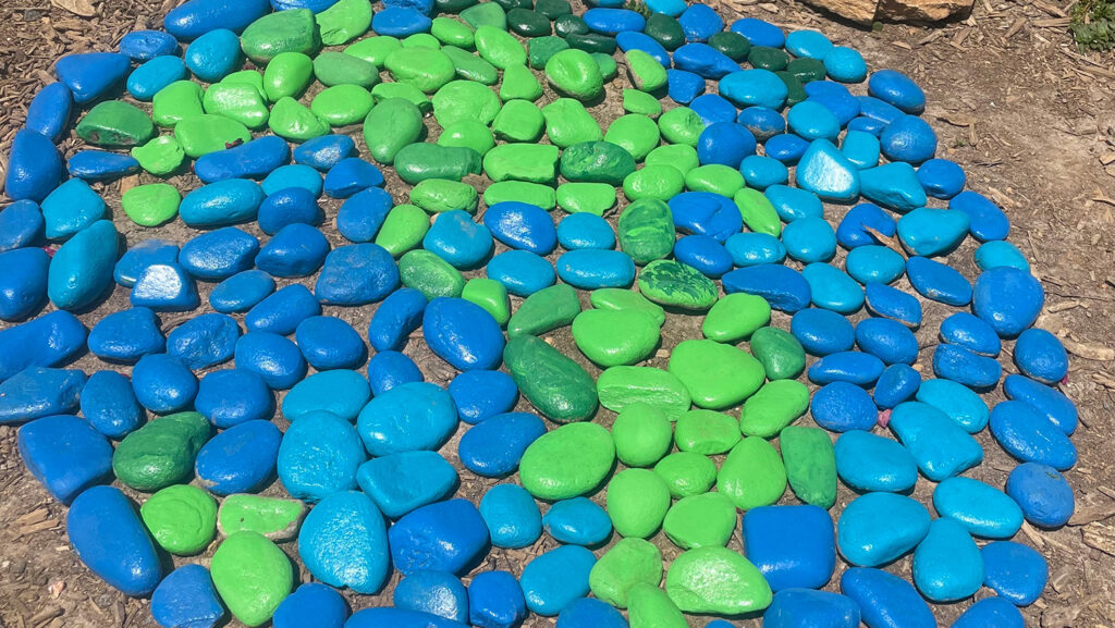 Blue and green painted rocks on ground
