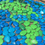 Blue and green painted rocks on ground