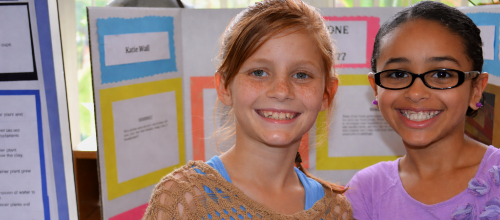two girls standing in front of science posters