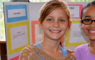 two girls standing in front of science posters